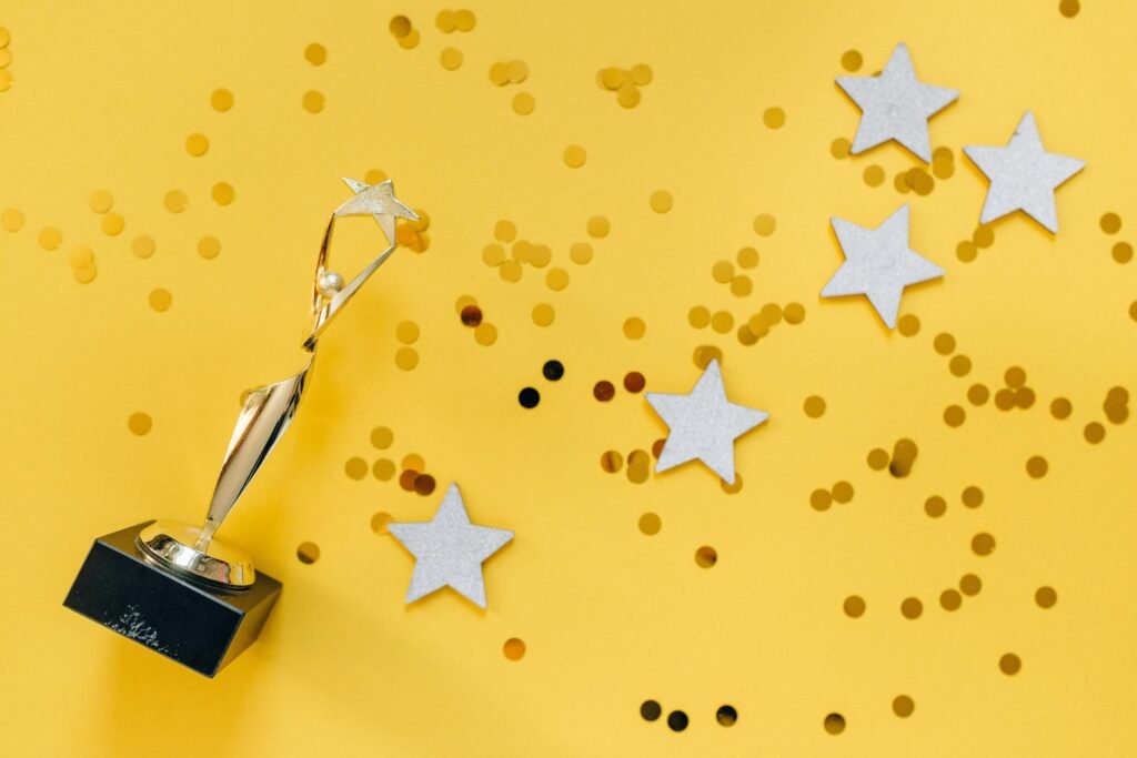 pexels-photo-6532373-6532373 Shiny golden trophy and stars on a vibrant yellow background, symbolizing success and victory.